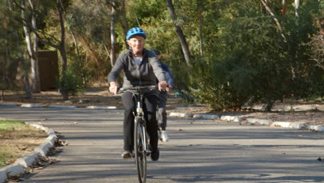 Pareja-Mayor-En-Bicicleta-Por-El-Parque-En-Cámara-Lenta