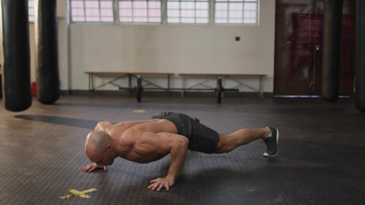 Male trainer pushing up, driving knee across, doing pushups for fitness with blue icons floating