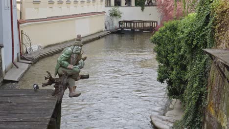 una vista de la estatua del troll con una pipa en un canal cerca del río vltava en praga, república checa