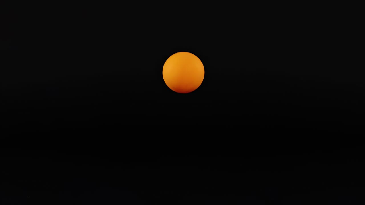 An orange ball moves vertically against a dark background, captured in a sequence of frames.