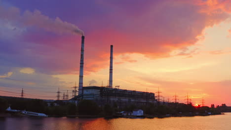 industrial area at sunset. factory near the river on the beautiful pink sky. harmful manufacture with smoke goes from industrial pipe in the evening.