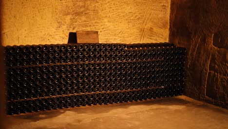 botellas de vino apiladas en un sótano débilmente iluminado