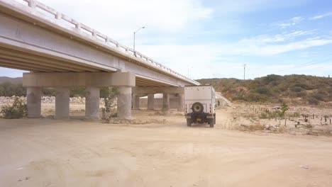 low aerial shot following a motor home driving under a highway in baja california.