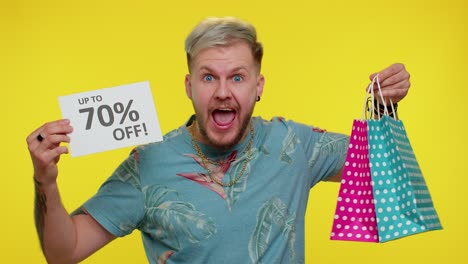 excited man holding shopping bags and a sign saying 'up to 70% off'