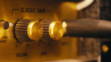 close-up of plugging a jack into a guitar amplifier and turning up the volume knob, live concert show, playing music on guitar tube amplifier.