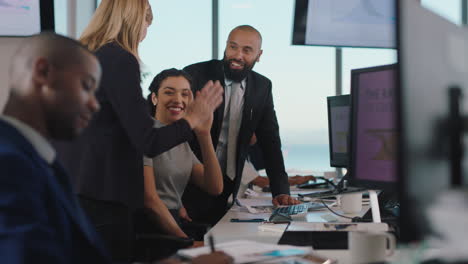 sales team celebrating success with high five looking at financial graph data on computer screen happy business people enjoying corporate victory achievement in office