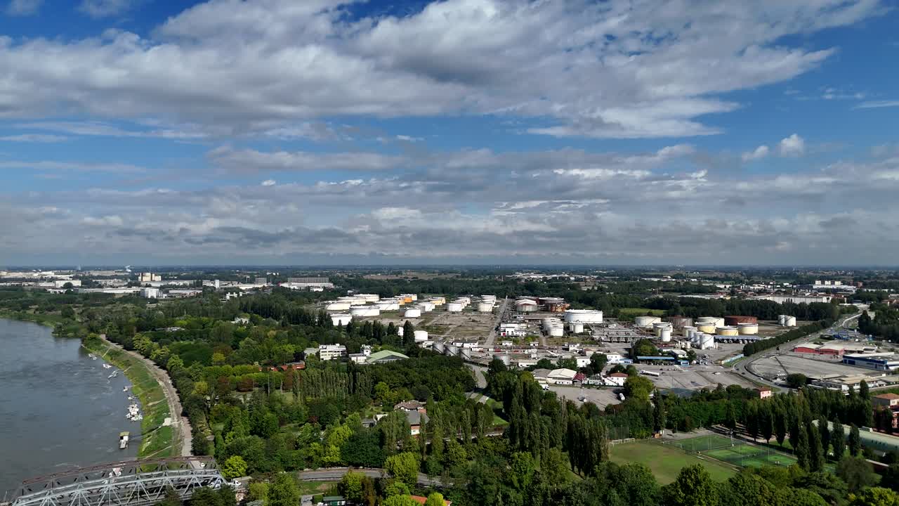Aerial view capturing Po River valley, industrial Cremona Tamoil refinery nestled beneath cloudy sky, revealing Lombardy's contrasting landscape