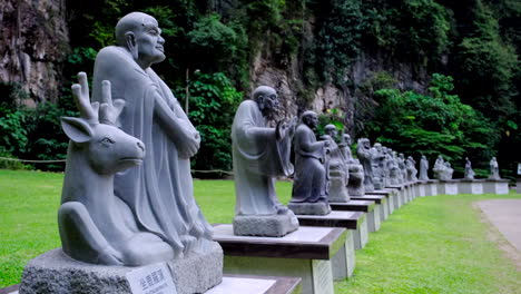 multiple buddha statues line up in the park with the mountain in the background