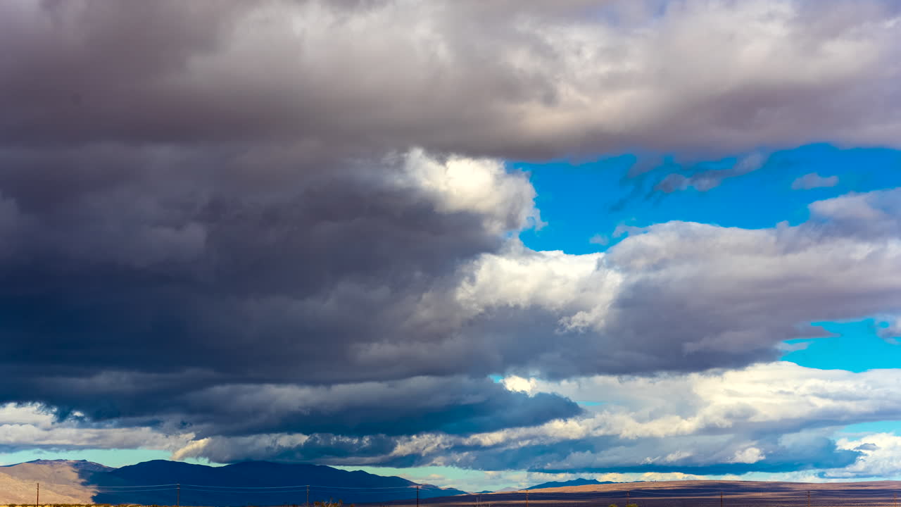 enormes nubes oscuras rodando por el accidentado paisaje del desierto de mojave amenazando lluvia - lapso de tiempo