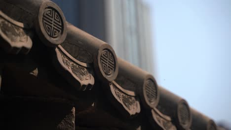 part of the ancient chinese roof with modern buildings in the background