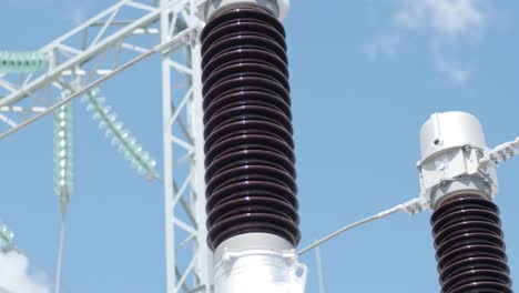 many high voltage electrical insulators in power substation against blue sky background