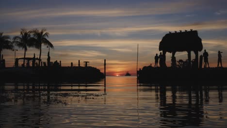 key largo sunset with palm trees and tiki hut on gulf