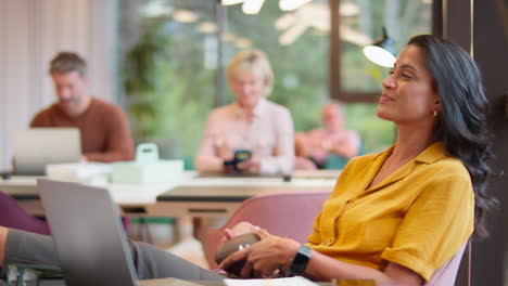 mature businesswoman with feet on desk in office catching small american football