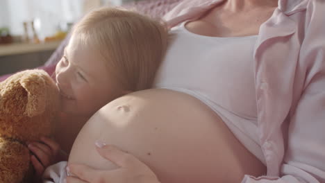 joyous girl holding toy and bonding with loving pregnant mother