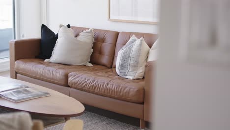 45 degree angle dolly shot of the living area in a high ceiling penthouse condominium unit showing the details of the leather sofa and coffee table during a sunny day