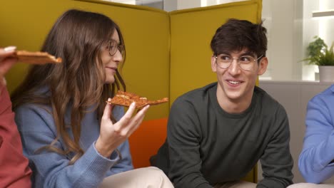friends sharing pizza slices in a modern office