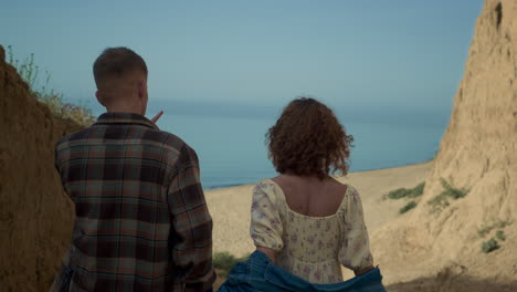 jóvenes amantes corriendo por la playa del océano. una chica atractiva agita el pelo sosteniendo la mano de un hombre.