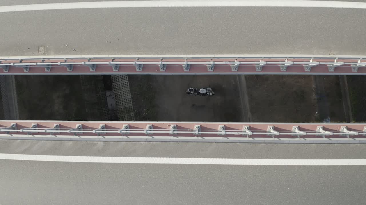vista aérea de drones de una motocicleta estacionada debajo de un puente a través de la brecha entre dos puentes en una carretera