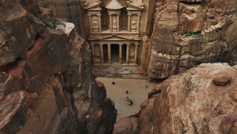 khazneh al-fira'un pharaoh's treasury in middle of sandstone cliffs in jordan - aerial tilt reveal