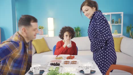 Happy-family-sitting-at-the-dinner-table-in-the-morning-eating-breakfast-together-and-having-fun.-Loving-married-couple.