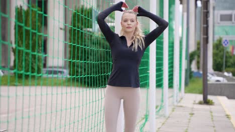 woman in sportswear posing by a fence