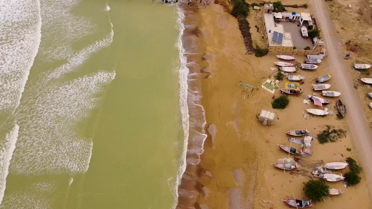 Allana Gadoor Village beach showing waves crashing on the coastline with many fishing boats