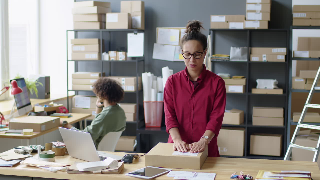 A woman is packing a cardboard box in an office