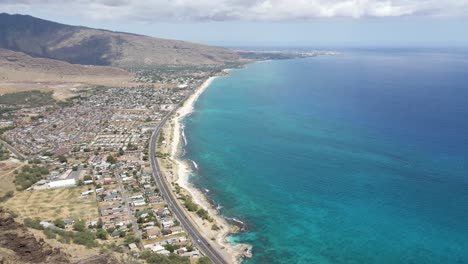 Highway-with-mountains-and-city-next-to-tropical-ocean-water-on-coast-of-tropical-island