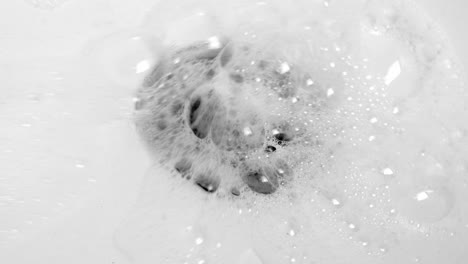 water splashing down in the stainless sink hole drain with lots of bubbles - high angle, close up