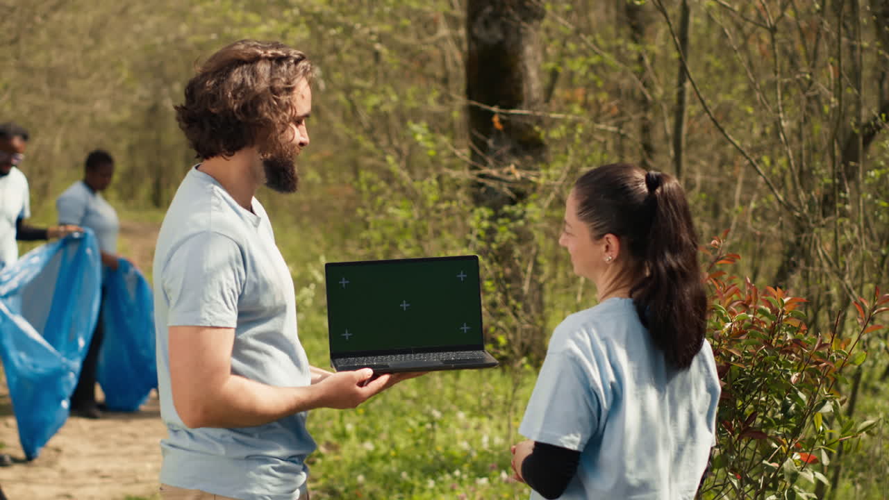 equipo de activistas climáticos y de la naturaleza usando una computadora portátil con pantalla verde cerca de un bosque