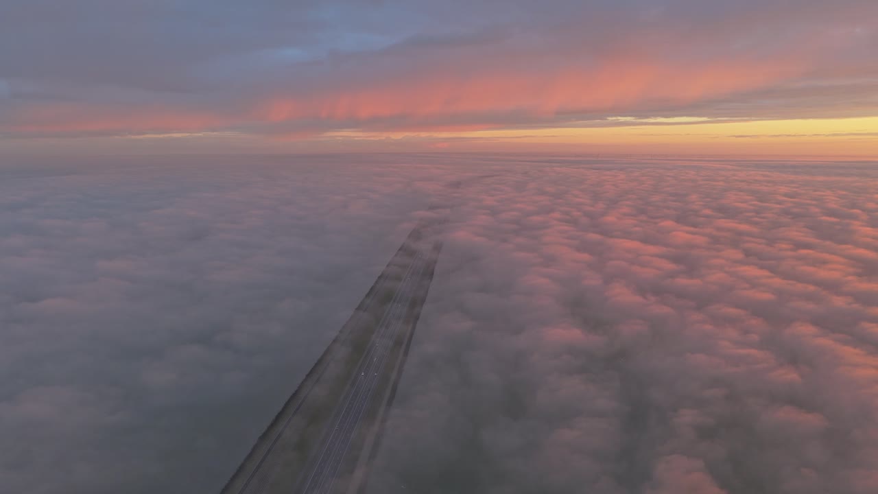 Luftfoto af Afsluitdijk-vejen ved solopgang, der skærer igennem de uendelige hollandske vidder.