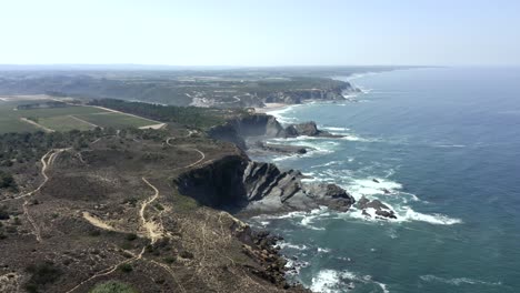 beautiful-aerial-footage-looking-over-the-clffs,-shoreina-and-surrounding-landscape-at-Zambujeira,-Portugal