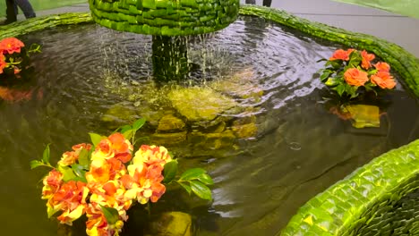 Water-droplets-cascade-into-a-fountain-adorned-with-blooming-flowers,-symbolizing-the-beauty-of-nature's-cycle-and-the-harmony-of-elements