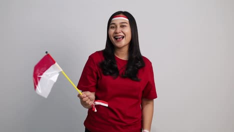 Indonesian woman standing holding red white flag to celebrates Indonesia independence day. Isolated on white