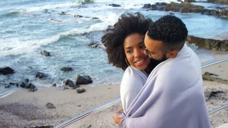 Couple-in-blanket-kissing-each-other-at-beach-4k
