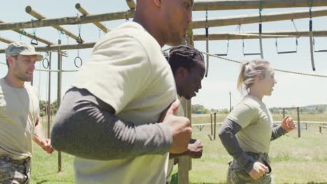 Diverse-fit-group-in-army-fatigues-running-in-the-sun-at-army-obstacle-course-in-field