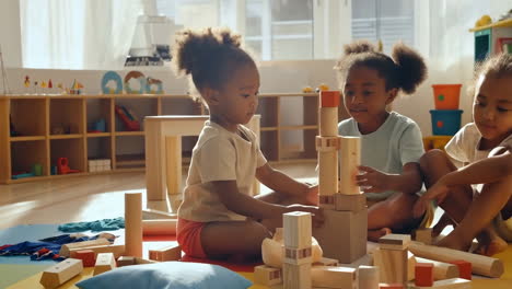 young girls playing with wooden building blocks in a classroom