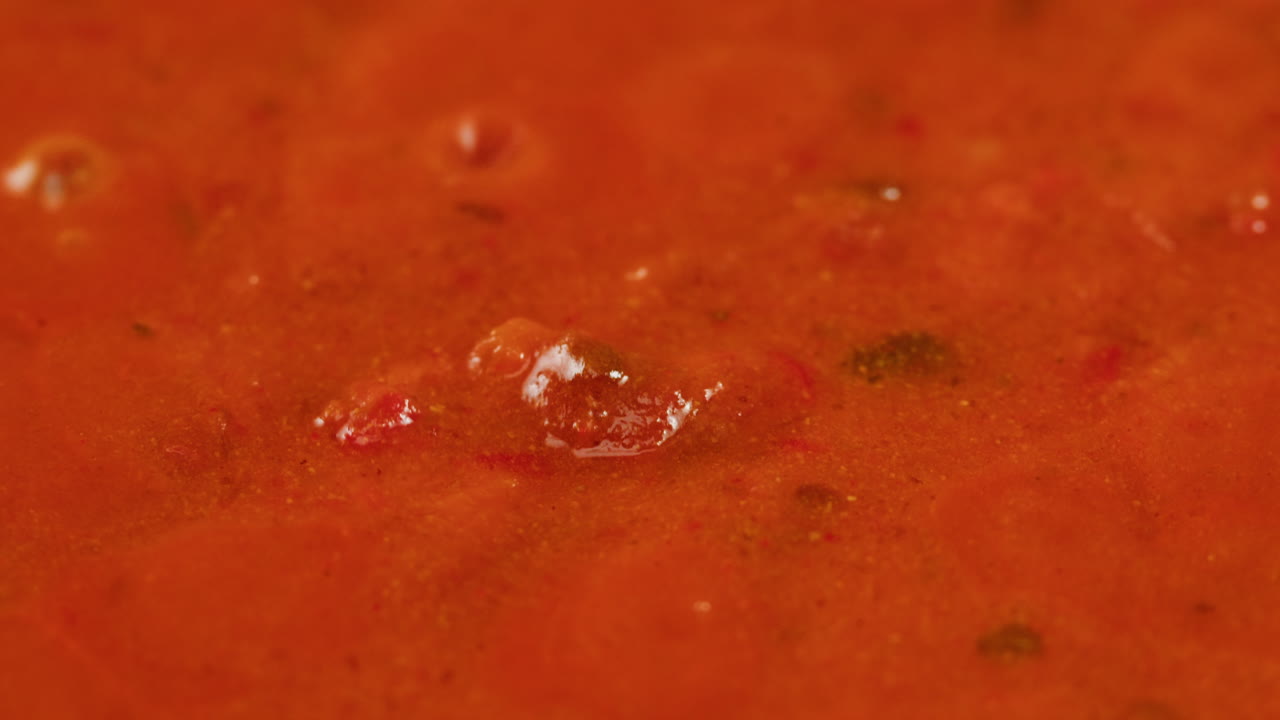 Chicken in tomato sauce is boiling on a frying pan with spices. Cooking tomato sauce curry with chicken fillet. Traditional Italian Mexican Asian dish. High quality studio shot for cafe, restaurant close up.