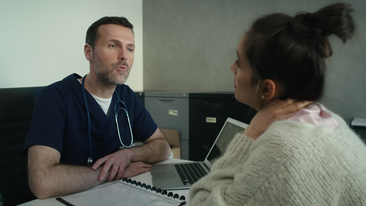 Paciente femenina caucásica escuchando el diagnóstico de una resonancia magnética sostenida por un médico.