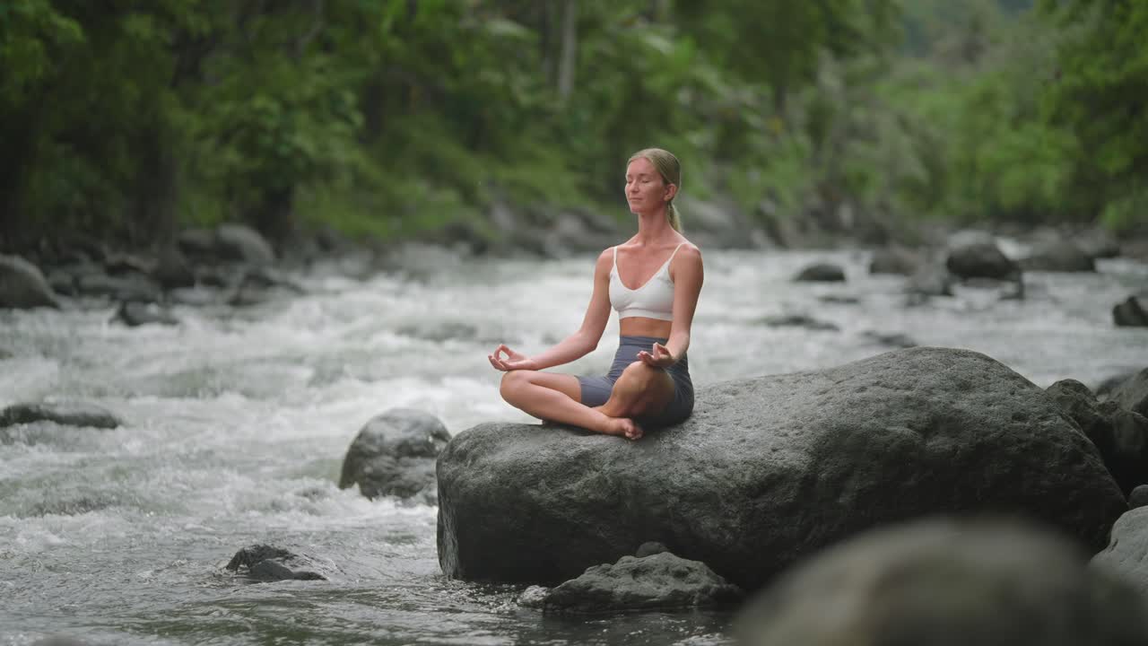 mujer relajándose de la ajetreada vida en la naturaleza, sentada en una pose fácil con las manos gyan mudra