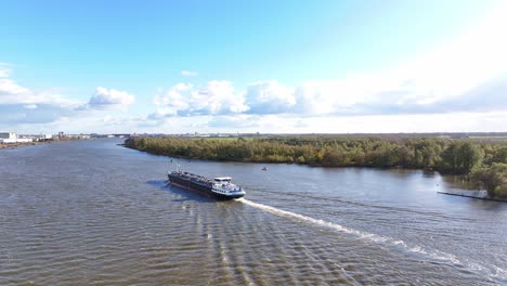 судно плывет по реке, создавая мягкие волны на поверхности воды.