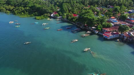 Vista-Aérea-De-Barcos-Anclados-En-El-Mar-Azul-Cerca-Del-Pueblo-Pesquero-En-El-Sur-De-Leyte,-Filipinas