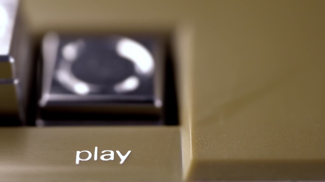 botón de reproducción de un grabador de cinta vintage presionado por un macro de dedo