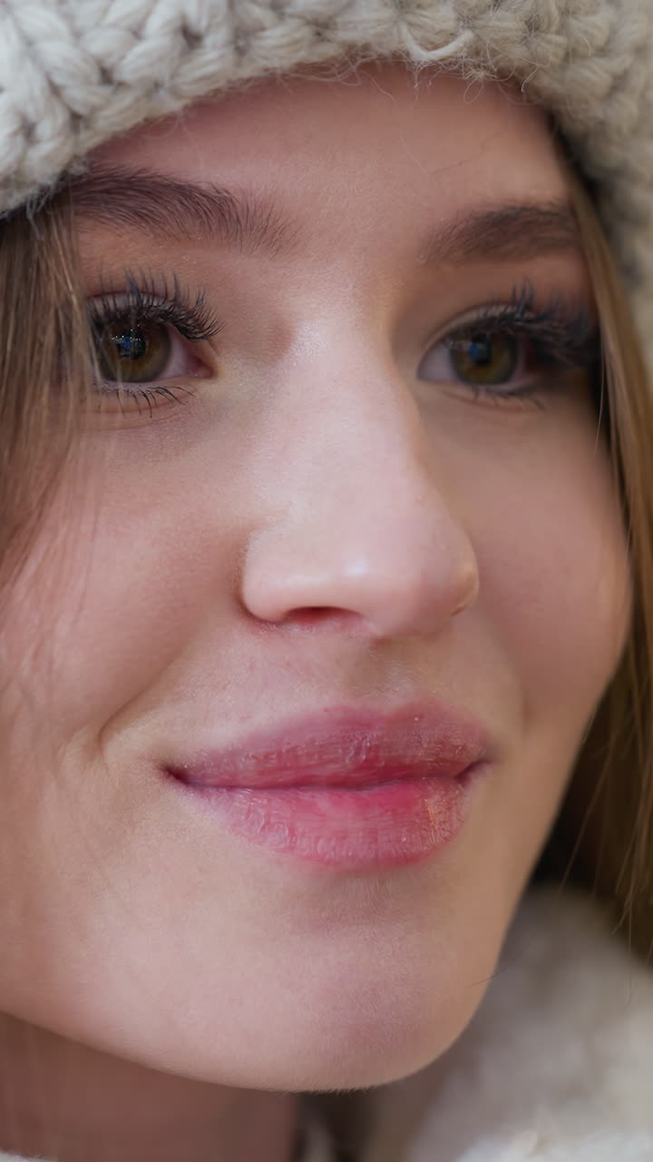 Close-up of elegant woman wearing a knitted beanie, pink lips radiating warmth and charm, soft glow and bokeh lights in the background add a dreamy aesthetic