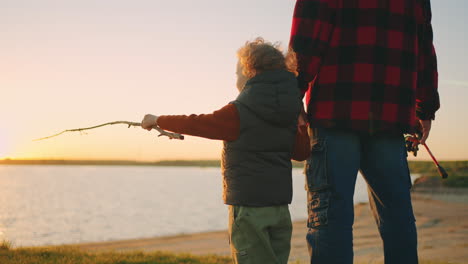 Glücklicher-Kleiner-Junge-Und-Sein-Vater-Genießen-Den-Wunderschönen-Sonnenuntergang-Am-See-Oder-Fluss-Und-Erholen-Sich-Mit-Der-Familie-In-Der-Natur