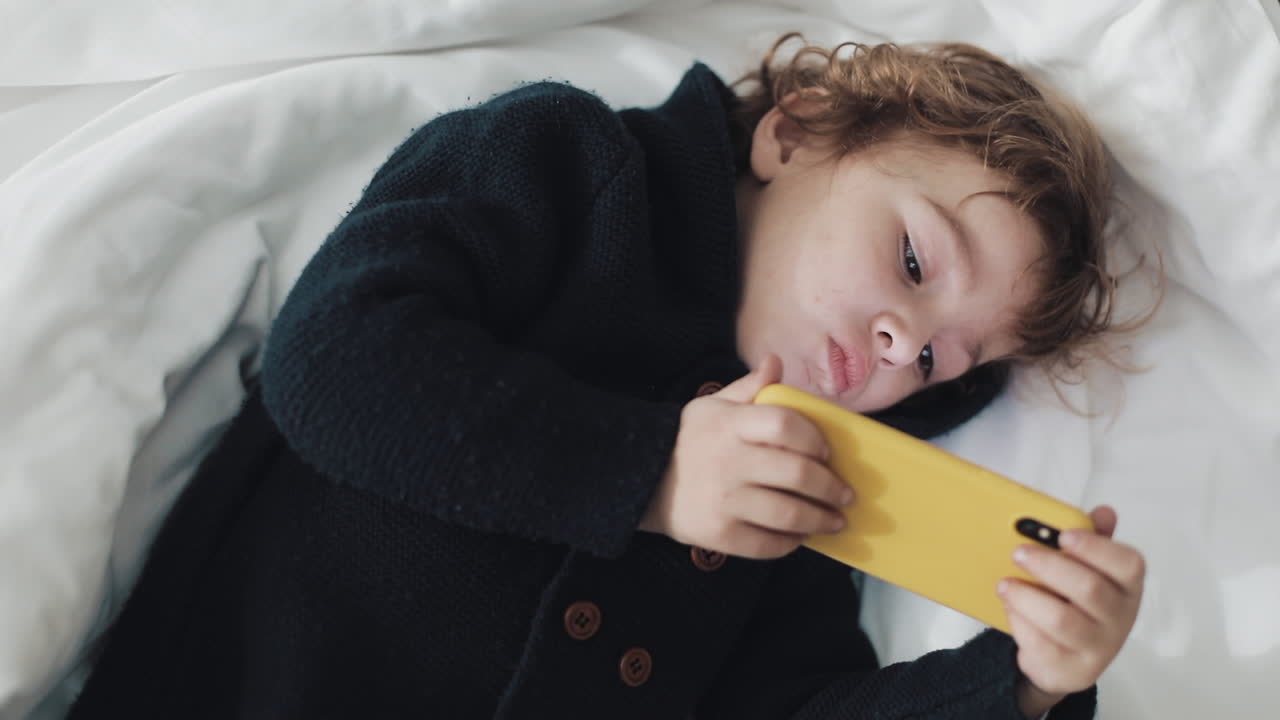Child using a smartphone in bed