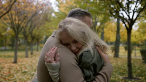 married couple hugging gently in autumn park