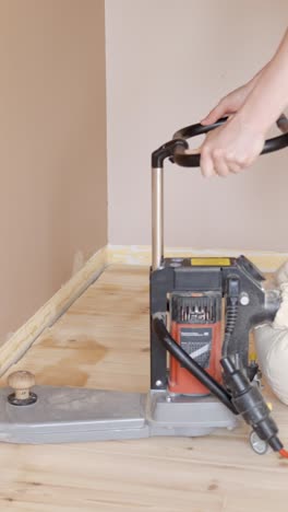 electric floor sanding machine operating on wooden floor, vertical video