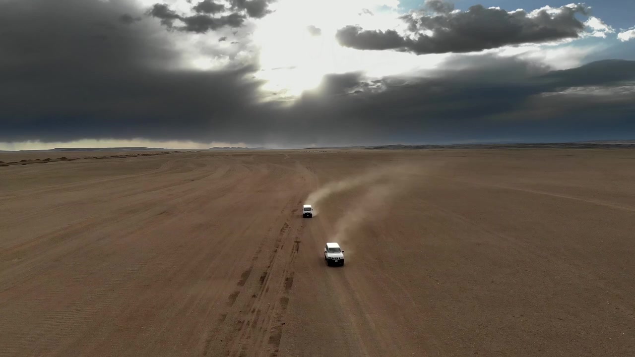 Due veicoli fuoristrada che attraversano un vasto paesaggio desertico