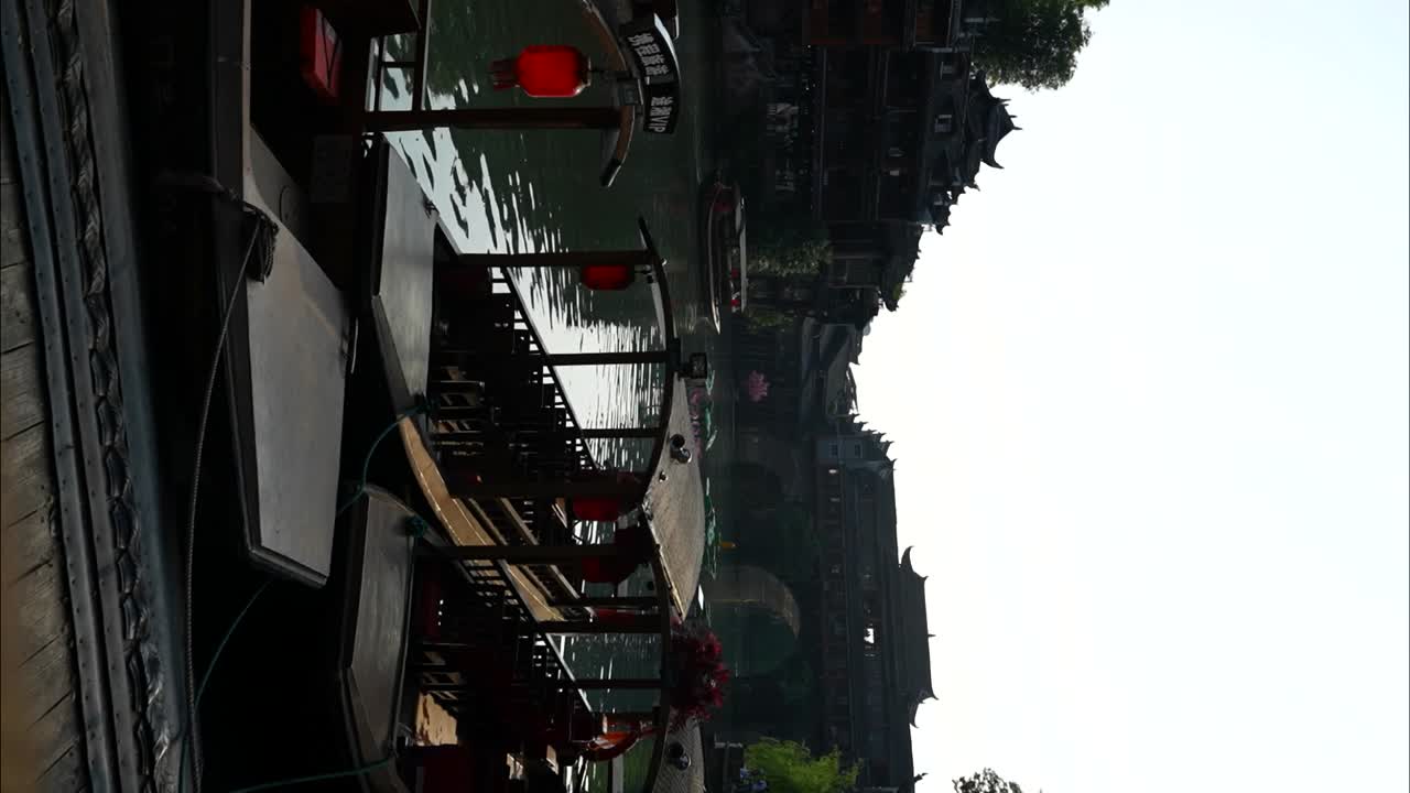 Traditional Chinese boats docked by the river at sunrise in Fenghuang Old Town, China. Vertical